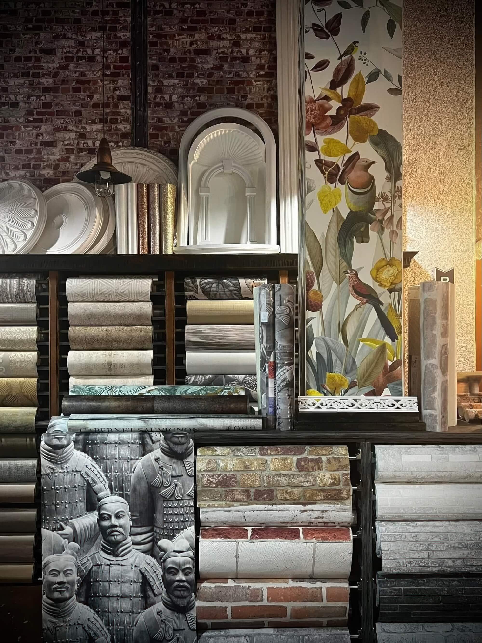 A wall-to-wall display of premium wallpaper rolls in various colors, textures, and styles.